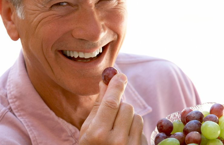 Un uomo che mangia dell'uva