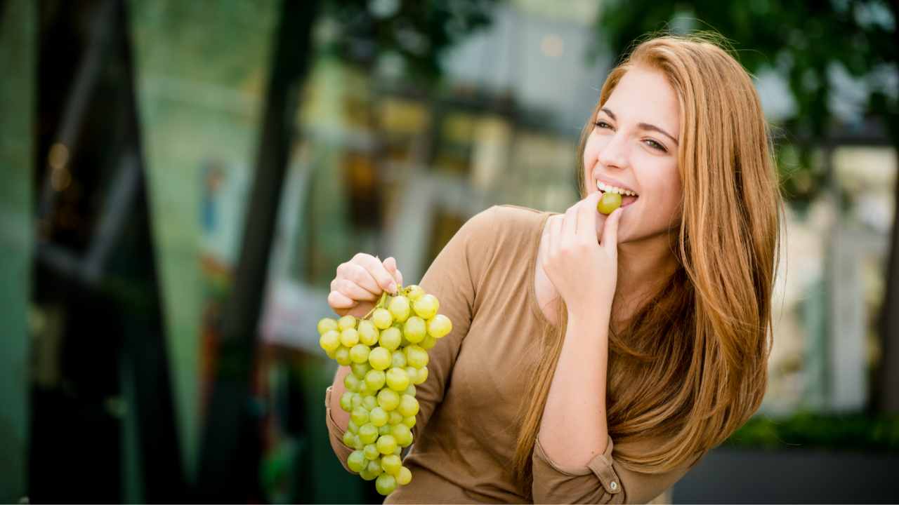 Una donna che mangia uva